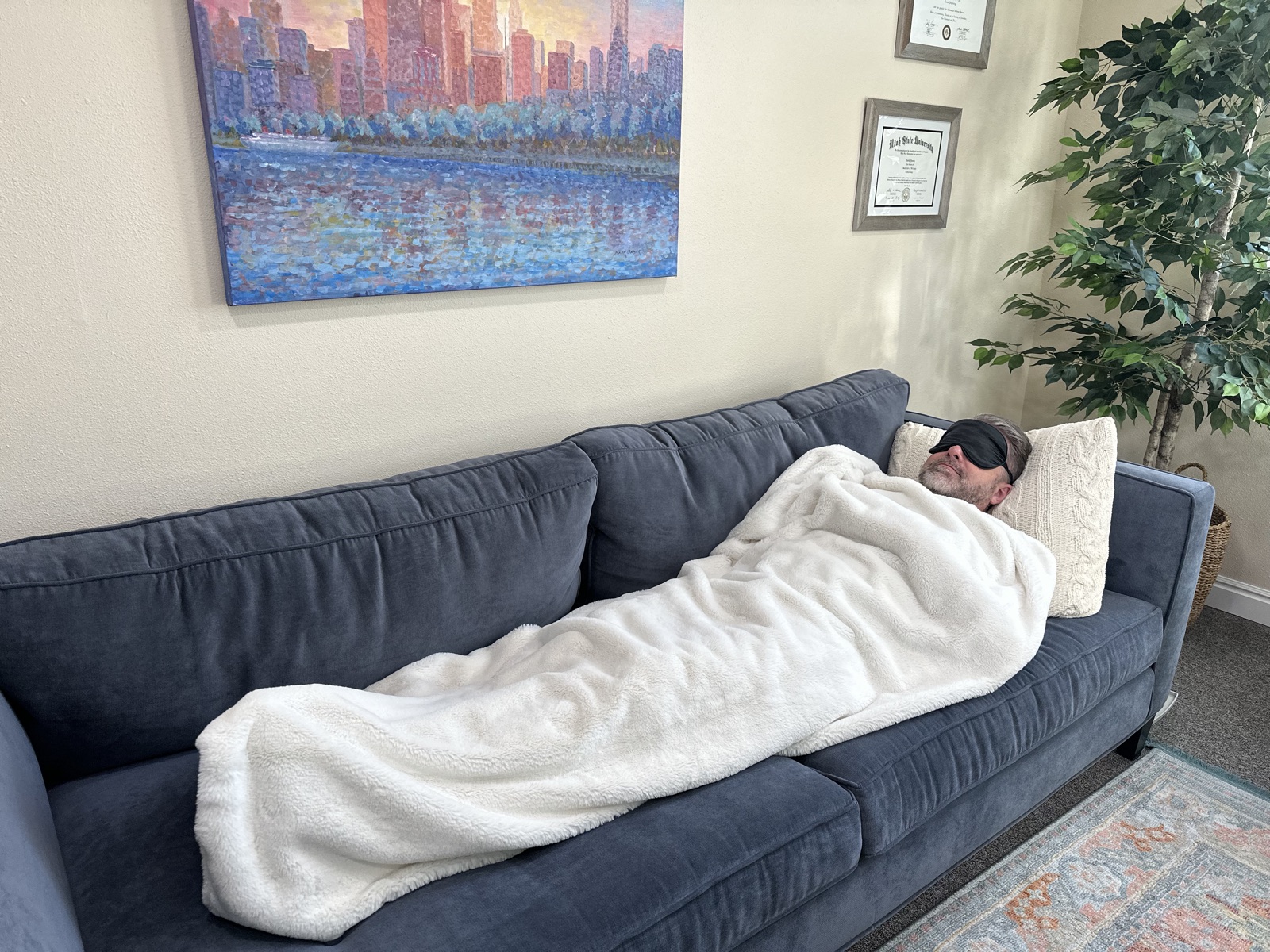 A one-on-one KAP medicine session set up in the clinic: a person resting on a couch under a blanket wearing an eye mask